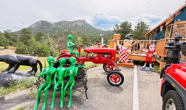 Whimsical roadside statues and a red vintage tractor near Estes Park, Colorado