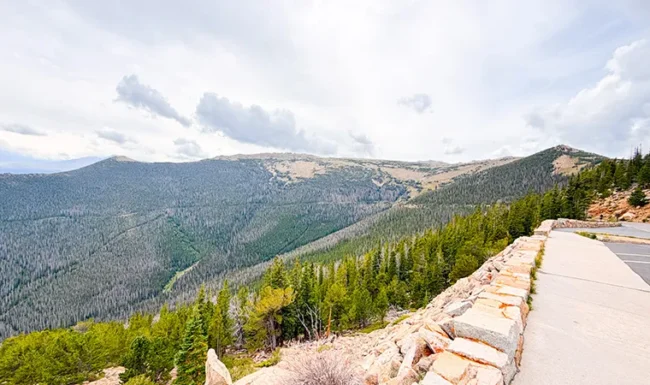 Paved overlook walkway and stone wall above the forested mountains of Rocky Mountain National Park
