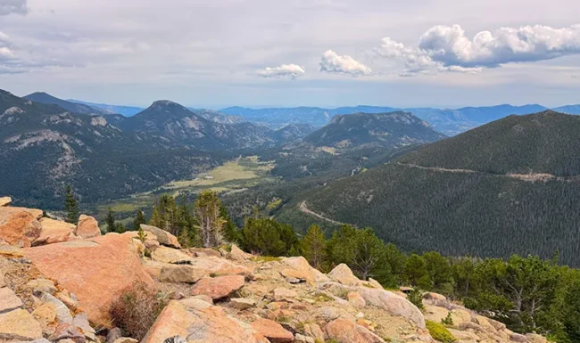 Mountain valley and forested ridges viewed from a rocky overlook along Trail Ridge Road