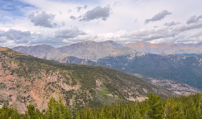 High-elevation mountain landscape with rugged peaks and alpine forest near Rainbow Curve Overlook