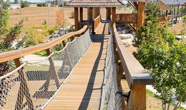 Elevated wooden bridge connecting play structures at Westminster Station Park Nature Playground