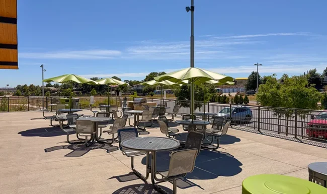 Covered picnic area with tables and green umbrellas at Westminster Station Park