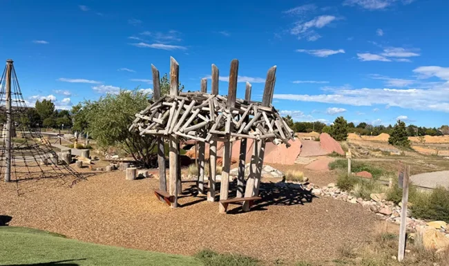 Rustic beaver dam play structure and climbing net at McKay Lake Park’s nature playground
