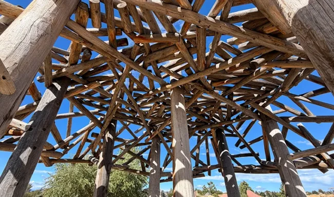 Rustic beaver dam log play structure and climbing net at McKay Lake Park’s nature playground