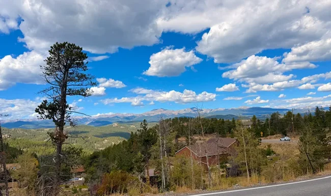Rocky Mountains view from CO-119 near Golden, Colorado, with pine forest and dramatic clouds