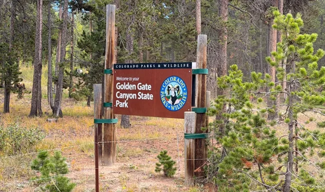 Golden Gate Canyon State Park entrance sign among pine trees in Colorado