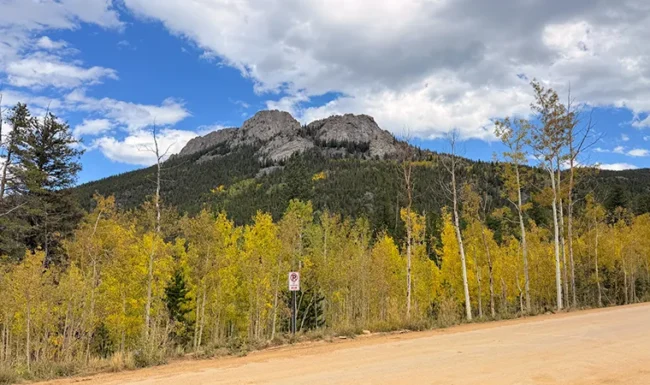 Mountain peak above golden aspens and a dirt road in Golden Gate Canyon State Park, Colorado