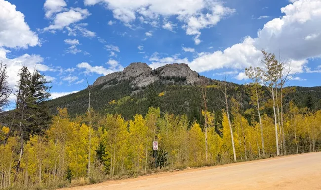 Mountain peak above golden aspens and a dirt road in Golden Gate Canyon State Park