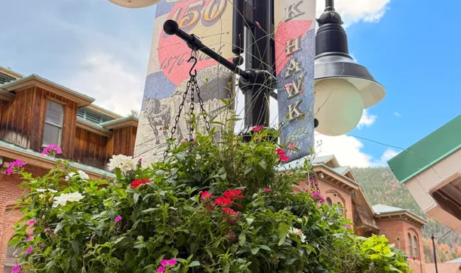 Historic-style streetlamp with hanging flower basket and 250 anniversary banner in downtown Black Hawk, Colorado