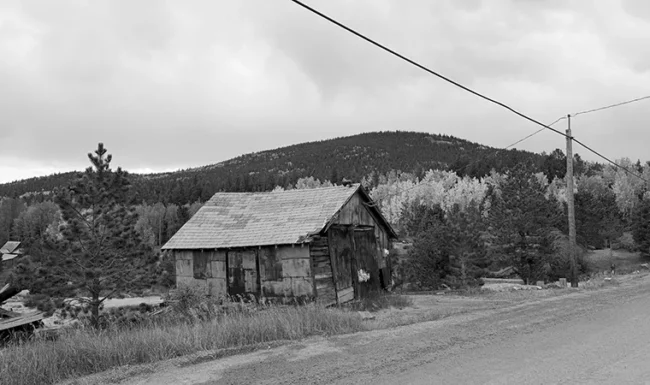 Weathered mining shack beside a dirt road and golden aspens near Central City, Colorado