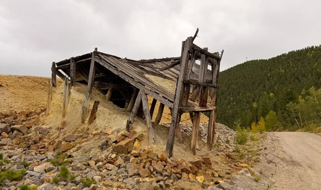 Weathered wooden mining ore bin beside a dirt road near Central City, Colorado