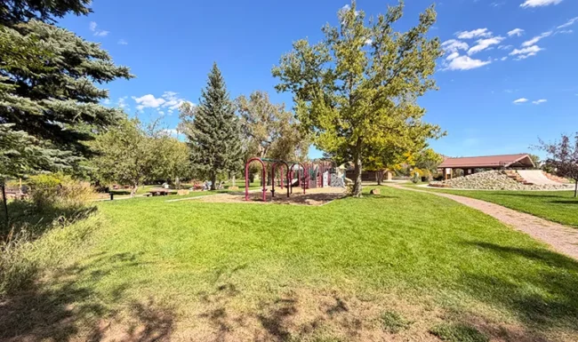Shaded lawn and walking path near the Bohn Park pavilion in Lyons, Colorado