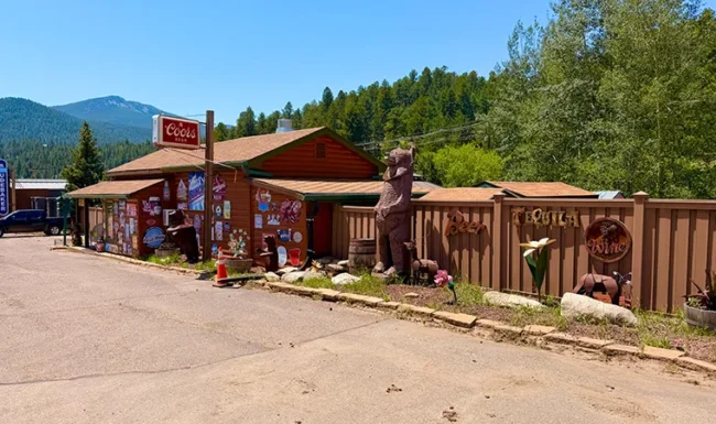 Rustic liquor store in Golden, Colorado, with vintage signs and a large wooden bear statue