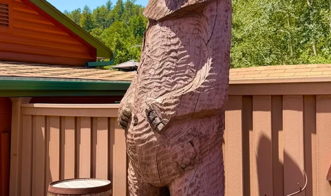 Tall carved wooden bear beside a barrel outside a liquor store in Golden, Colorado