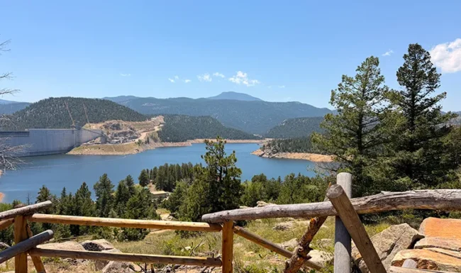 Gross Reservoir and dam viewed from a rocky overlook with a rustic wooden railing