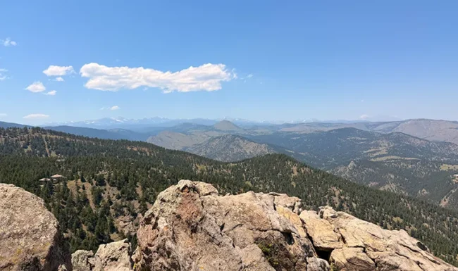 Rocky ledge at Lost Gulch Overlook with forested valleys and distant mountain peaks