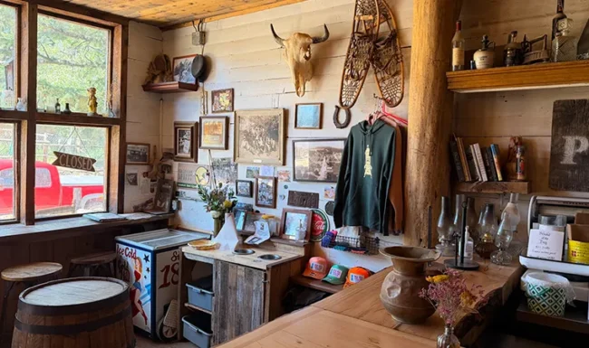 Rustic corner inside Gold Hill General Store with framed photographs, snowshoes and a mounted animal skull.