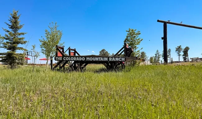 Wooden wagon displaying “The Colorado Mountain Ranch” sign in a grassy meadow near Gold Hill, Colorado.