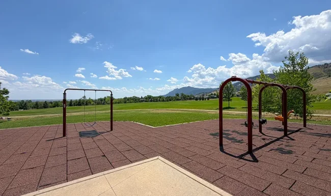 Playground swings with open lawn and mountain views at Foothills Community Park in Boulder Colorado