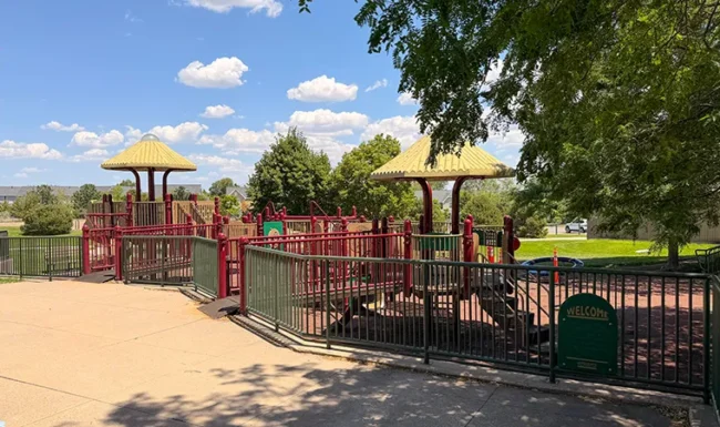 Fenced playground with climbing structures at Foothills Community Park in Boulder Colorado