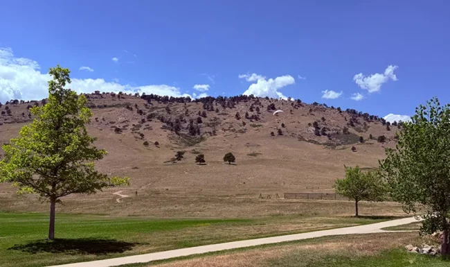 Paraglider descending over open space at Foothills Community Park in Boulder Colorado
