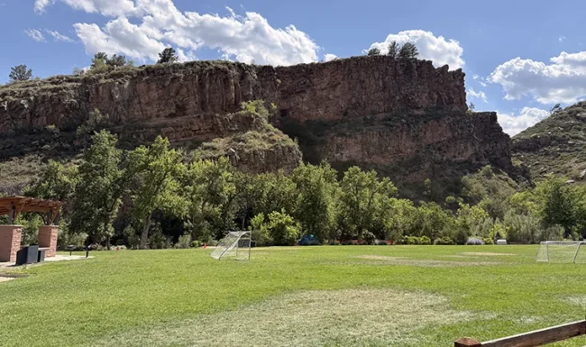 Large grassy field with soccer goals below sandstone cliffs at LaVern M. Johnson Park