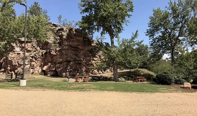 Picnic tables and grassy open space beside sandstone rock formations at LaVern M. Johnson Park