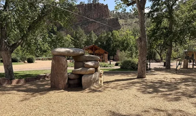 Stone climbing and nature play features beneath trees at LaVern M. Johnson Park