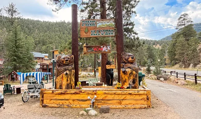 Rustic Ponderosa Lodge sign and carved bear sculptures along Fall River Road in Estes Park