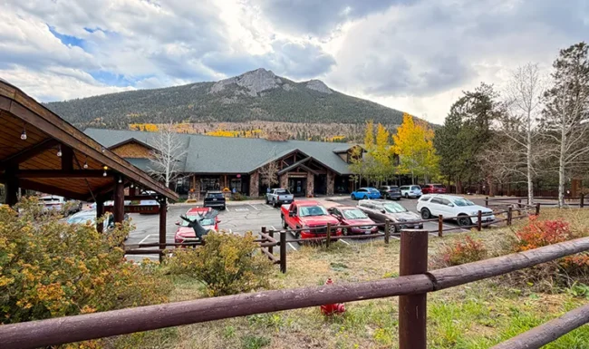 Fall River Gateway Visitor Center buildings and parking area beneath Rocky Mountain peaks